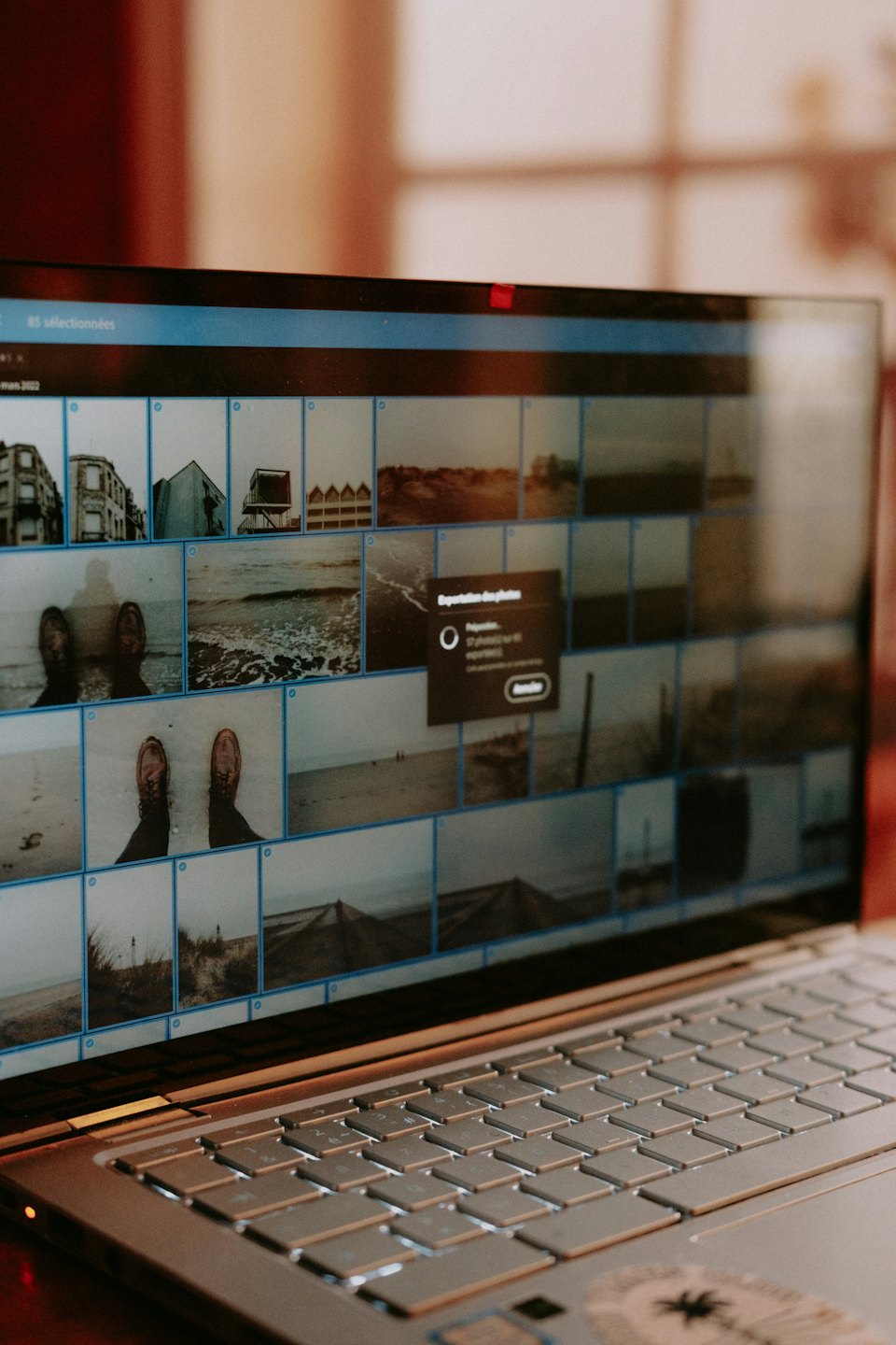 Laptopskärm visar miniatyrbilder av strandfoton och en exportdialogruta.